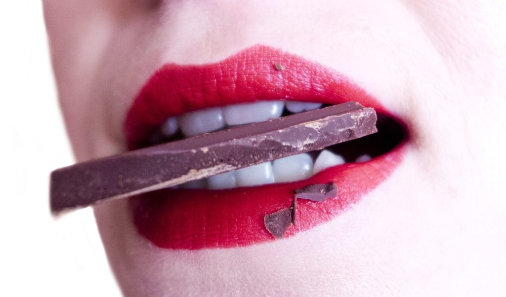 žena drží mezi zuby čokoládu